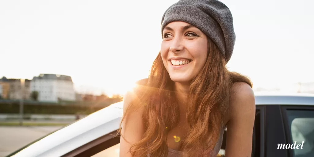 Female millennial wearing hooding and hanging torso out of car